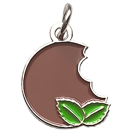 A dark brown cookie next to two leaves of mint. 