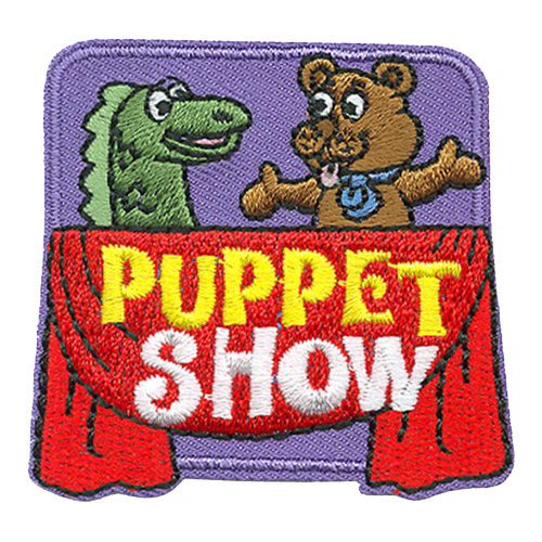 A dragon and a bear puppet are acting out a scene. A red throw is draped over the stage with the words Puppet Show.