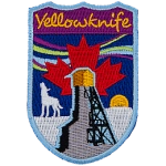 The name Yellowknife is above the northern lights and a howling wolf. A red maple leaf is in the middle of the sky.
