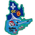 This patch is in the shape of the Canadian province of Quebec. From top to bottom, the Flue-de-lis, a jug of maple syrup, hockey stick and puck, Bonhomme, and Quebec City.