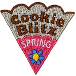 The words Cookie Spring Blitz are on a cookie slice with pink icing and a blue flower.