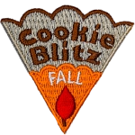 The words Cookie Blitz Fall are stitched on a cookie slice with orange icing and a red leaf.