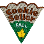 The words Cookie Seller Fall are on a cookie slice with green icing and a yellow leaf.