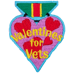 A heart-shaped badge with the words Valentines For Vets in the center.