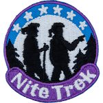 Two silhouettes hike between trees. The words Nite Trek are below them, and the moon is behind them with six stars.