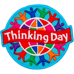 A colourful globe is circled by rainbow-coloured people holding hands. A banner that says Thinking Day is across the middle.