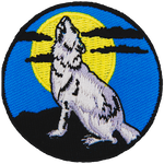 A lone wolf howls at a full moon in this circular patch.