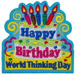 A two-tiered birthday cake with candles and the words Happy Birthday on it. Below the cake are the words World Thinking Day.