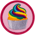 A rainbow-frosted cupcake on a pink background.