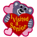 A teddy bear hugs a heart that says I Visited A Senior.