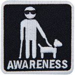 A white stick figure wearing sunglasses and holding a walking stick and the leash of a guide dog. The word Awareness is below.