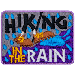 The words Hiking In The Rain surround two brown shoes walking up a hill in the rain.