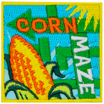 The words Corn Maze are on two arrows. An ear of corn is in the foreground.