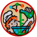 A ginger boy with a chef hat and a lab coat pours a beaker of bubbling green liquid into a blue bowl. A complex molecule floats above the chef's head.