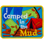 A person wearing bright green boots splashes in a mud puddle. The words I Camped in the Mud are overlayed atop the image.