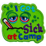 A green patch with a sad face. The words I Got Sick At Camp are on it.