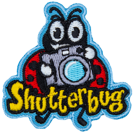 A ladybug holds up a retro camera. The word Shutterbug is stitched across the bottom.  Photography.