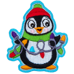 A happy penguin is wearing a toque, and scarf, holding a string of Christmas lights in his flippers.