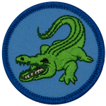 A green alligator with its tooth-filled mouth open facing left on a blue background.