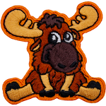 A baby moose sitting on its bottom and staring at the viewer with big eyes.
