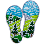 Two boot prints have images of nature within them. From the top down are the sun, clouds, waves, mountains, hills, forest, fields, and bushes.