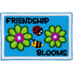 Two green flowers are on either side of a ladybug and bumblebee. The text around them reads Friendship Blooms.