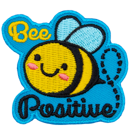 A cute bee has dots for eyes and a big U-shaped smile. The words Bee Positive are stitched above and below the bee. 
