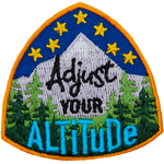 Stars sit above a mountain peak and forest. The text Adjust Your Altitude is in the center of the crest.