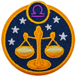 This circular crest displays the scales of justice surrounded by stars. The sign of Libra sits above it.