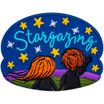 A boy and a girl stand on a grassy hill and look up at the starry sky. The text Stargazing is embroidered amongst the stars.