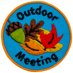 A pile of several leaves and an acorn are in the center of this patch. The words Outdoor Meeting are stitched around it.