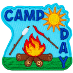 A marshmallow and hotdog roast over a fire. The words Camp Day are above and on the right.