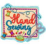 A square piece of fabric with three spools of thread, scissors, a sewing needle and the words Hand Sewing on top of it.