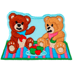 Two teddy bears sit on a picnic blanket eating red and green apples on a clear day.
