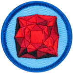 A red garnet is in the centre of a circular blue badge.