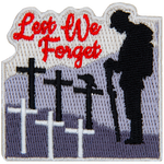 A soldier stands with his head bowed in front of several crosses. The words Lest We Forget are in the sky.