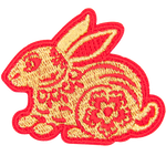 A gold rabbit with a red outline and floral details on its body.