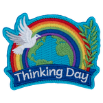 A rainbow arches over the globe. A dove is in front of it. The words World Thinking Day are on a ribbon across the bottom.