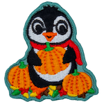 A cute penguin in a red scarf holding an orange pumpkin.