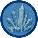 A blue, pointed crystal sits on a light blue background.