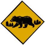 A monochromatic bear walks across a yellow caution sign.