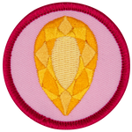 A golden citrine is in the centre of a circular pink badge.