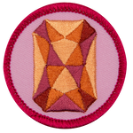 An orange sapphire is in the centre of a circular pink badge.