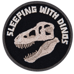 The words Sleeping With The Dinosaurs are above a T-Rex skull.