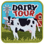 A black and white dairy cow faces the viewer underneath the words Dairy Tour.