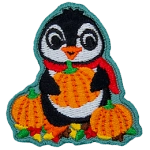 A cute penguin in a red scarf holding an orange pumpkin.