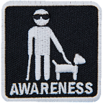 A white stick figure wearing sunglasses and holding a walking stick and the leash of a guide dog. The word Awareness is below.