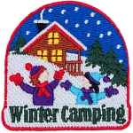 A cabin is nestled amongst snowy hills as kids frolic in the snow during winter camping.