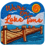 A blue, sunny sky above white puffy clouds. A wooden dock extends into a calm lake. We're On Lake Time, sits in the sky.