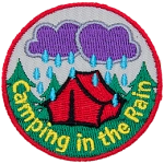 Dark clouds pour rain down on a tent in the woods during a night of camping in the rain.